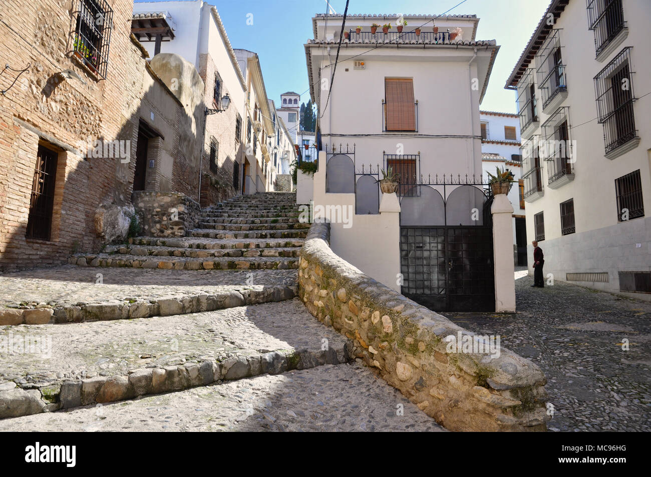 Old medieval street with stone pavement and stairs, and white typical old houses at the Albaicín arab district in Granada (Andalusia, Spain) Stock Photo