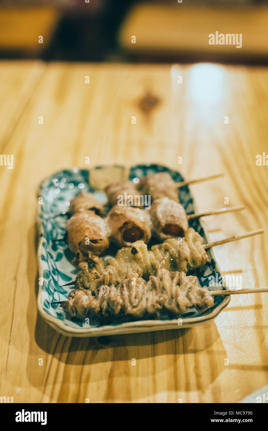 Japanese food in izakaya restaurant at night. chicken skin in skewer. Stock Photo