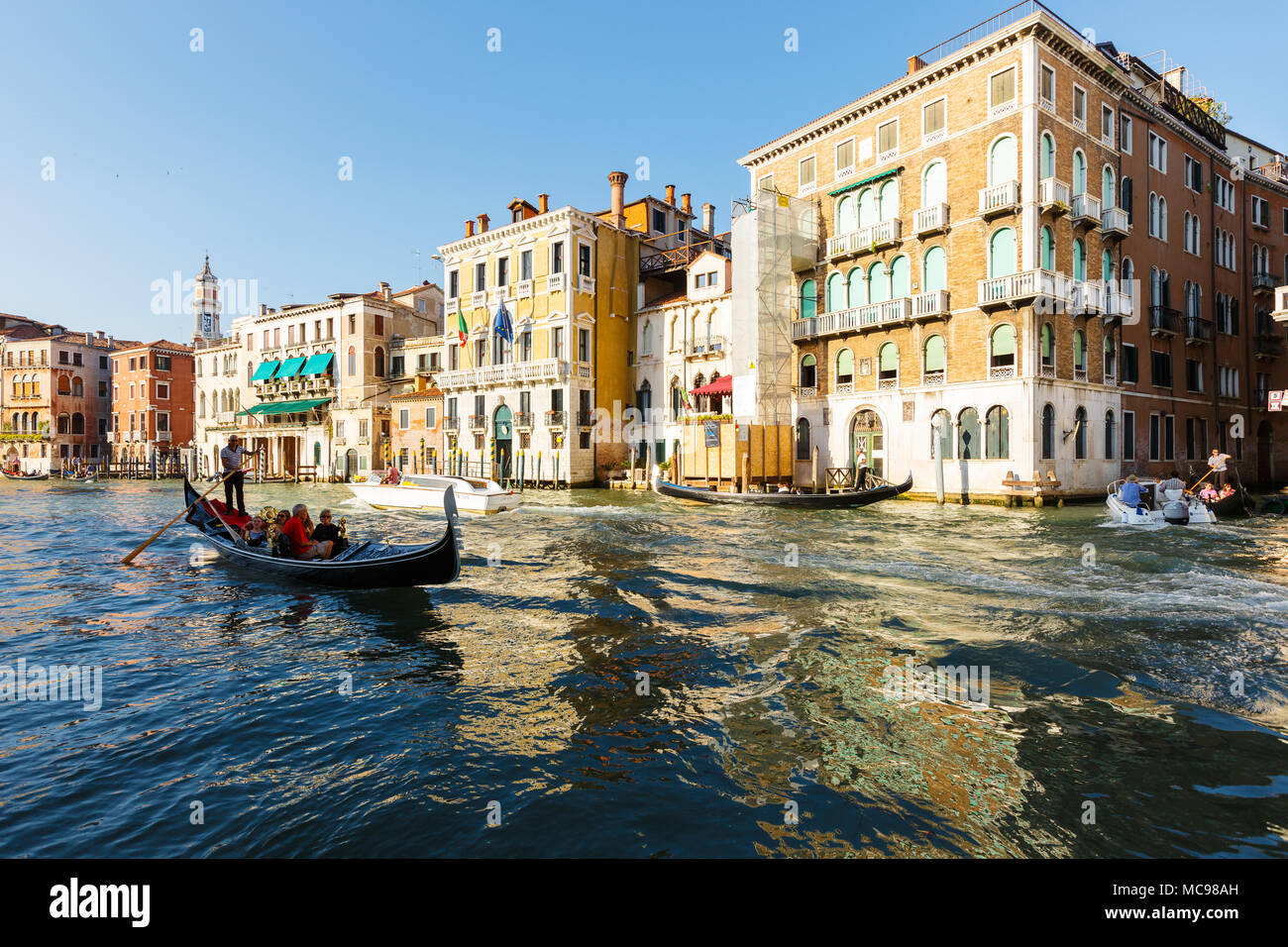 Venice, Italy - June, 21, 2013: Typical view to Venice city, to Grand canal, many tourists people enjoy a rest on gondolas and pleasure boat. Campanil Stock Photo