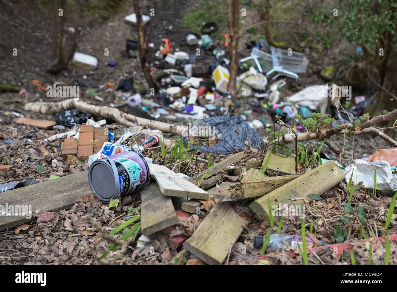 Piles of fly tipped rubbish including plastic, tyres, black bags, shoes are pictured in wasteland Stock Photo
