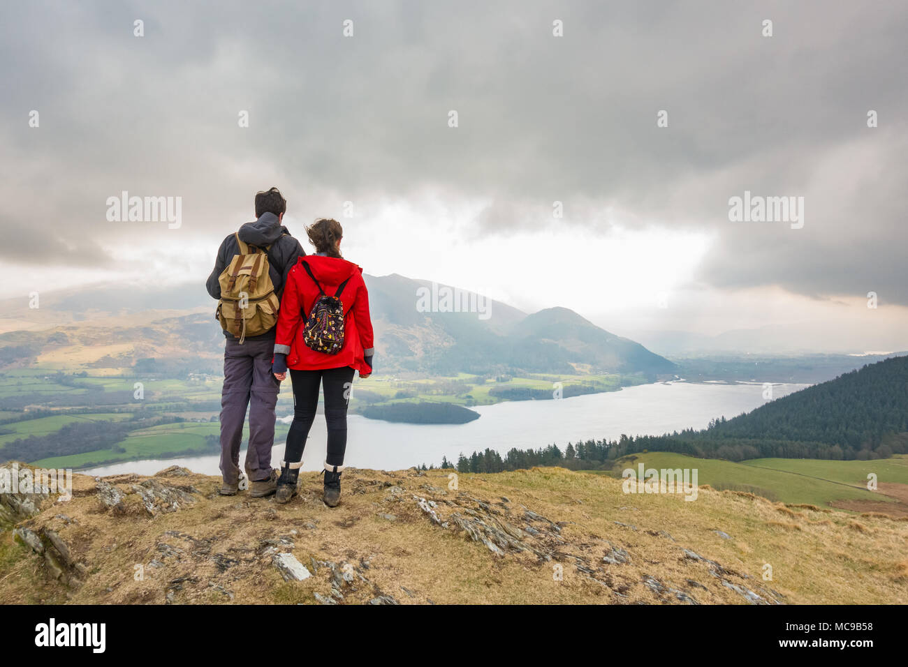 Lake district view - two walkers looking at the view of Bassenthwaite Lake and the Skiddaw range from Sale Fell, Lake District, Cumbria, England, UK Stock Photo