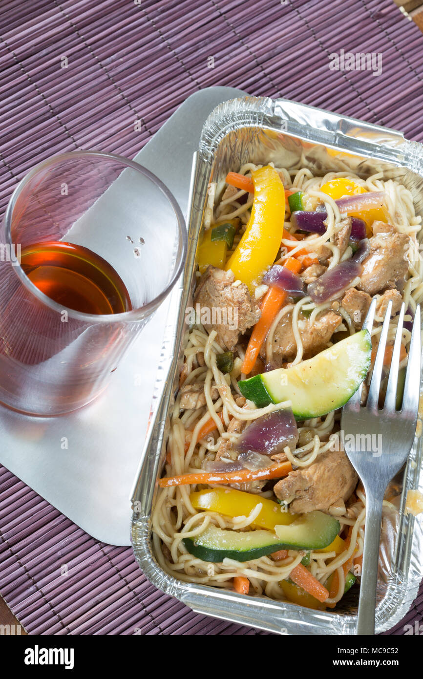 Chinese takeaway of Chicken noodle stir fry in a foil delivery dish