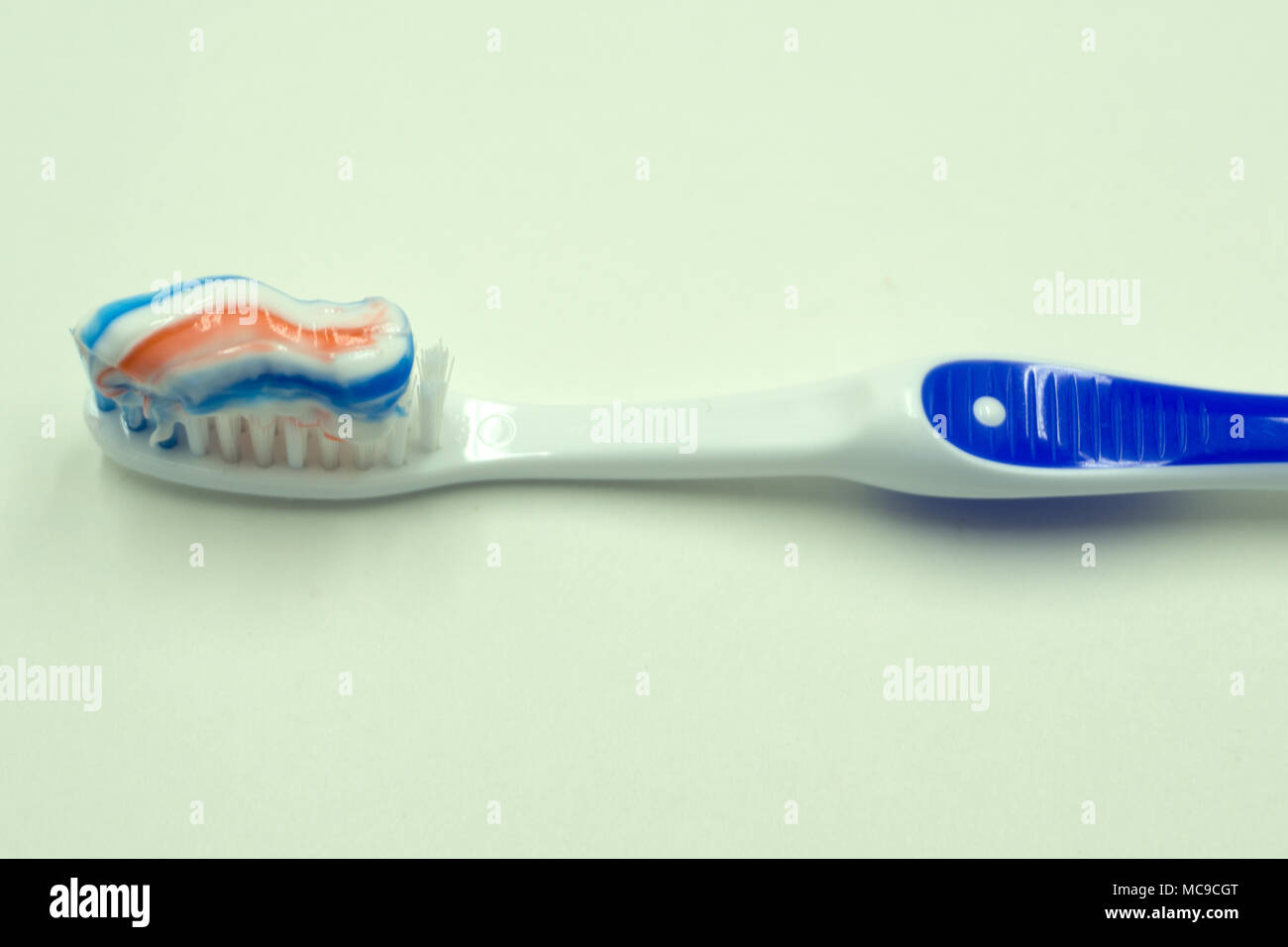 Toothpaste squeezed on the toothbrush on blue background Stock Photo