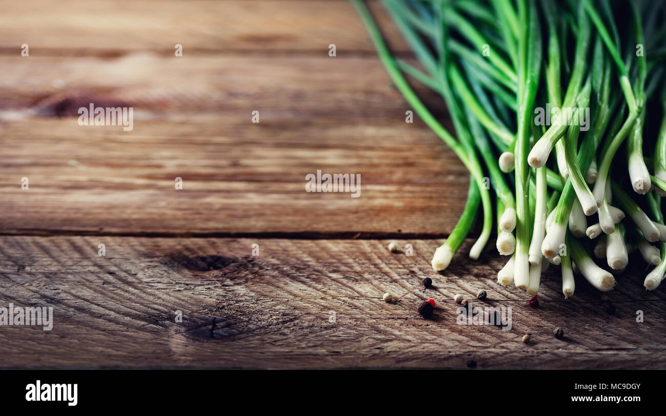 Bunch of fresh organic green onions, scallions on wooden background with pepper. Copyspace. Stock Photo