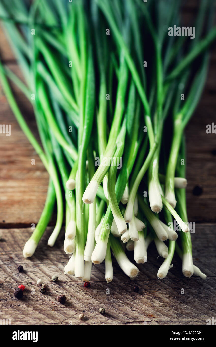 Bunch of fresh organic green onions, scallions on wooden background with pepper. Copyspace. Stock Photo