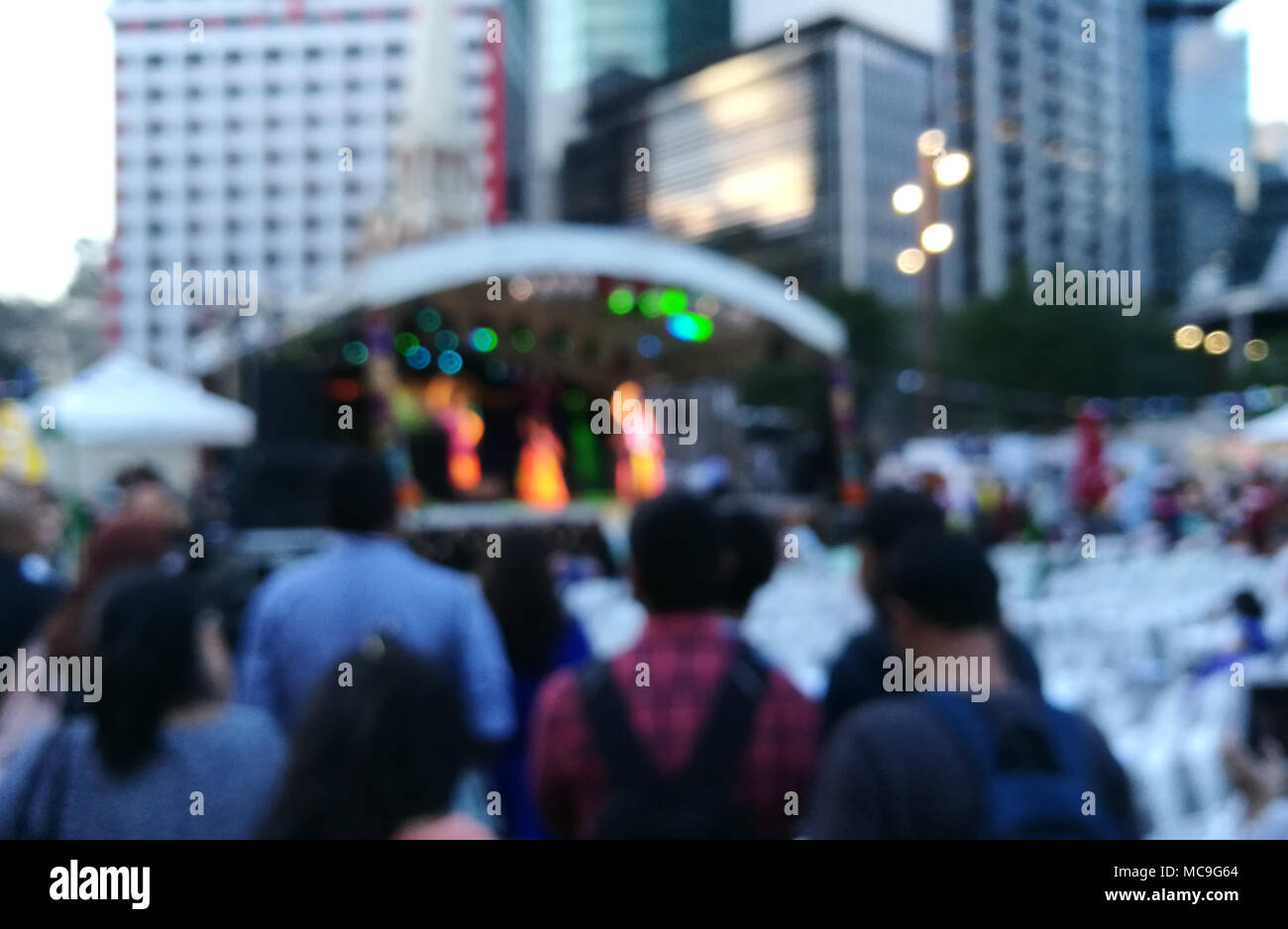 Defocused scene of crowd of people attending public concert celebrating New Year festival in city in Evening Stock Photo