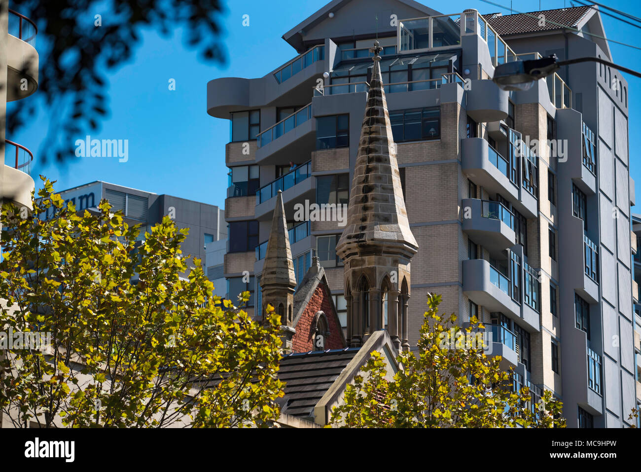 Street trees and the spire of the historic Chinese Christian Church (formerly Congregational Church) with apartments at rear in Milsons Point, Sydney. Stock Photo