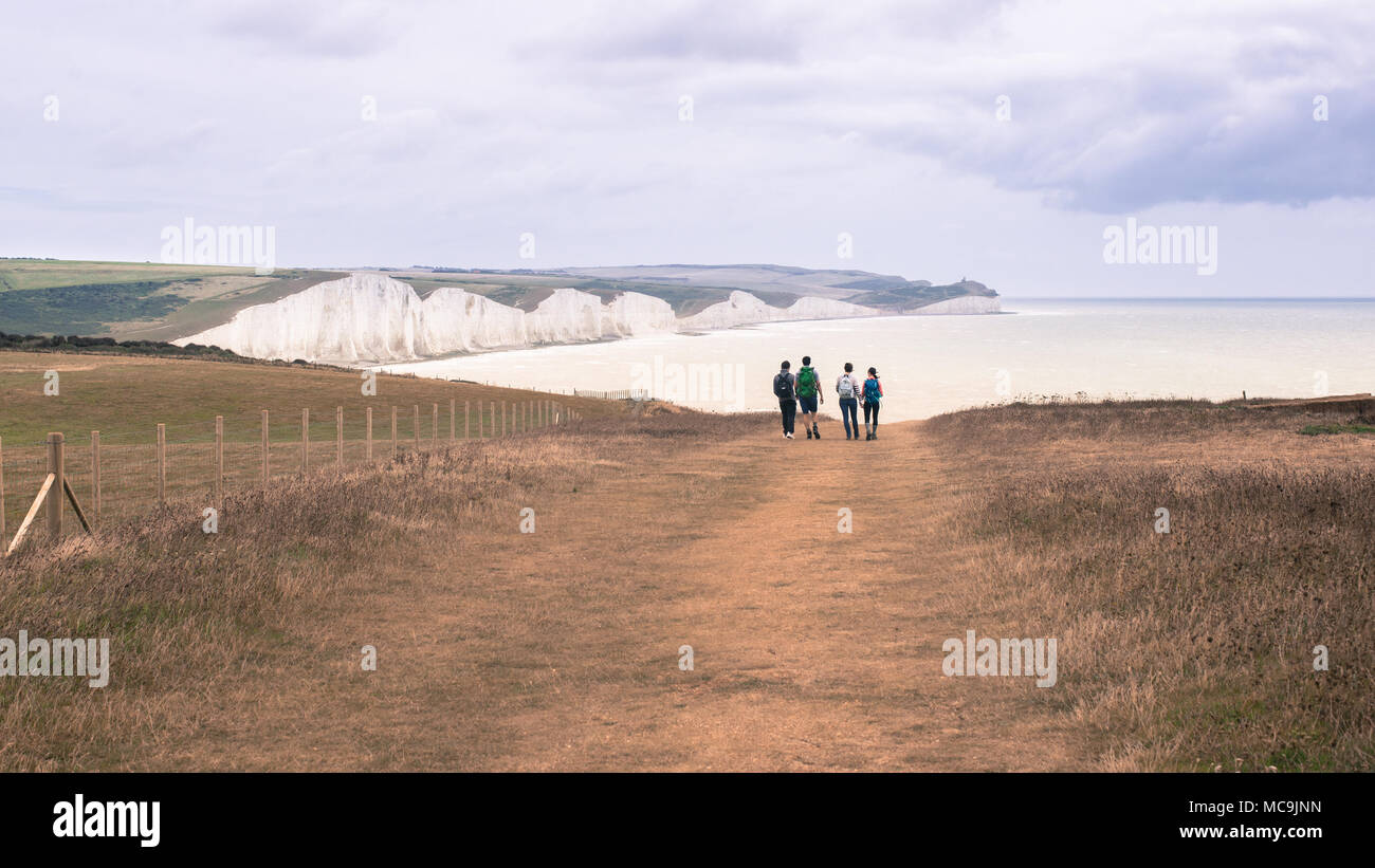 Seven sisters, Seaford, UK - 4 September 2016: Group of four people in the distance walking along the famous Seven Sisters path view beatiful view of  Stock Photo