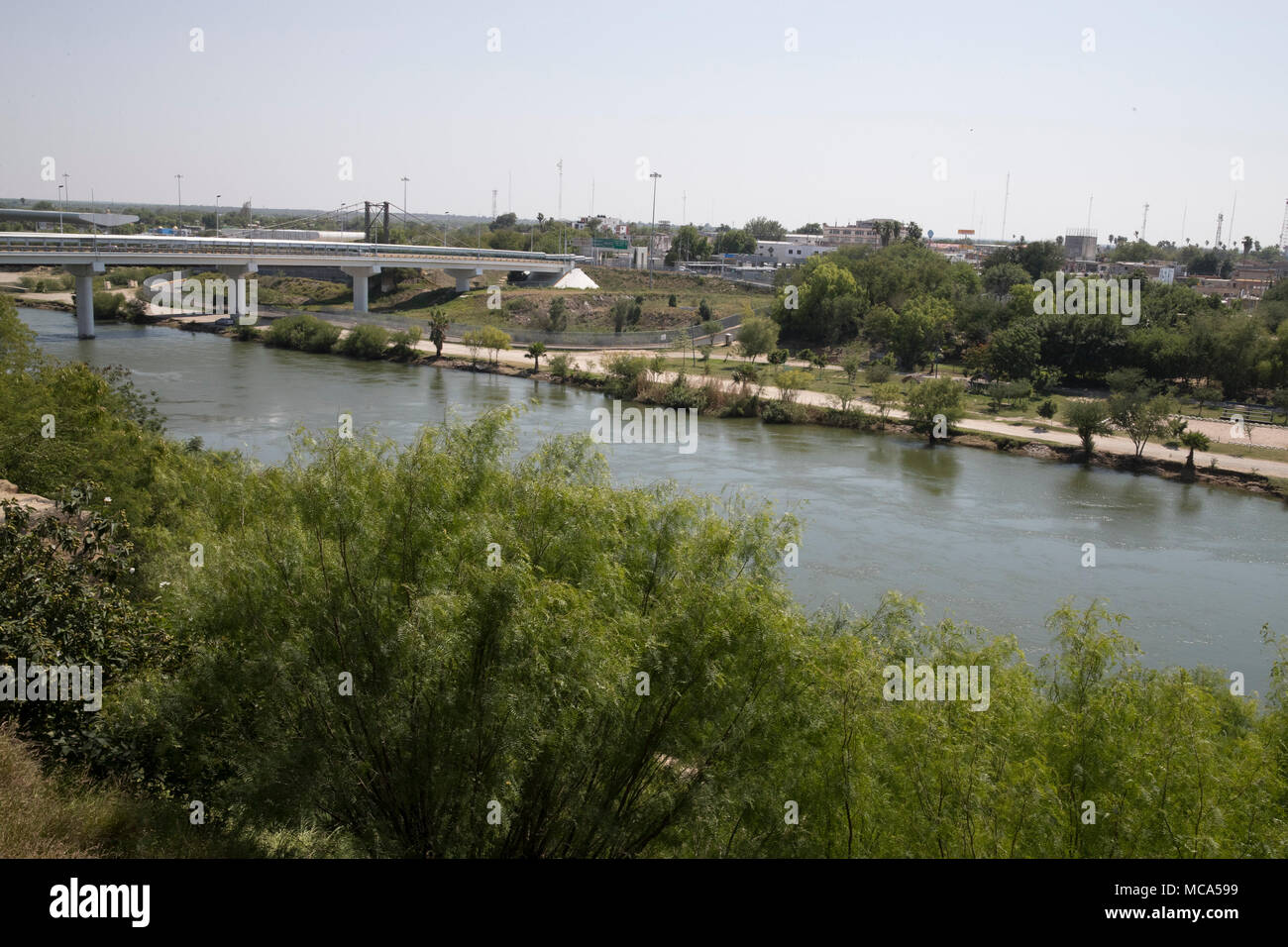 The Rio Grande River flows southward between the bluffs of Roma, TX., and the Mexican city of Ciudad Miguel Aleman to the right. Stock Photo