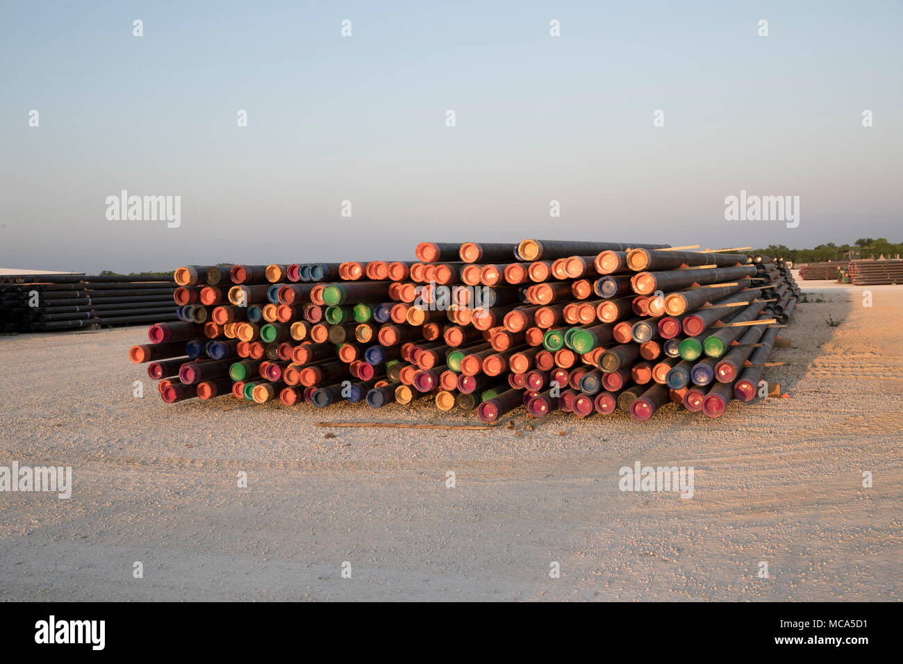 Drilling pipe with colored end caps sit stacked in a yard off Highway 16 near the oil fields in