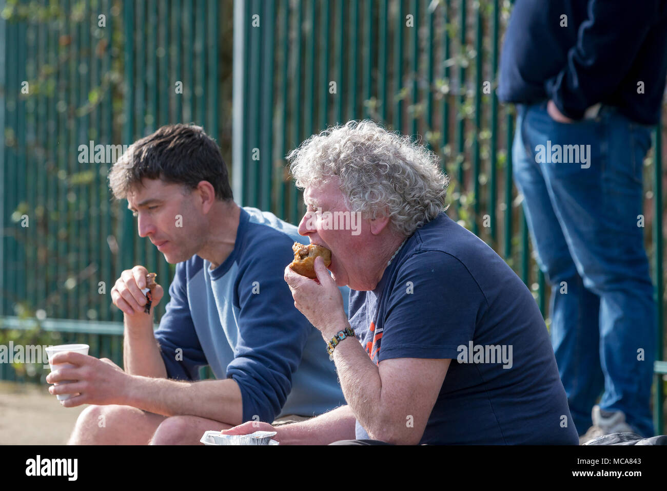 Two supporters of Warrington Town eat a snack at half time of the match at Throstle Nest, Farsley during the game between Warrington Town FC and Farsley Celtic on 14 April 2018 where Warrington won 2 - 0 Credit: John Hopkins/Alamy Live News Stock Photo
