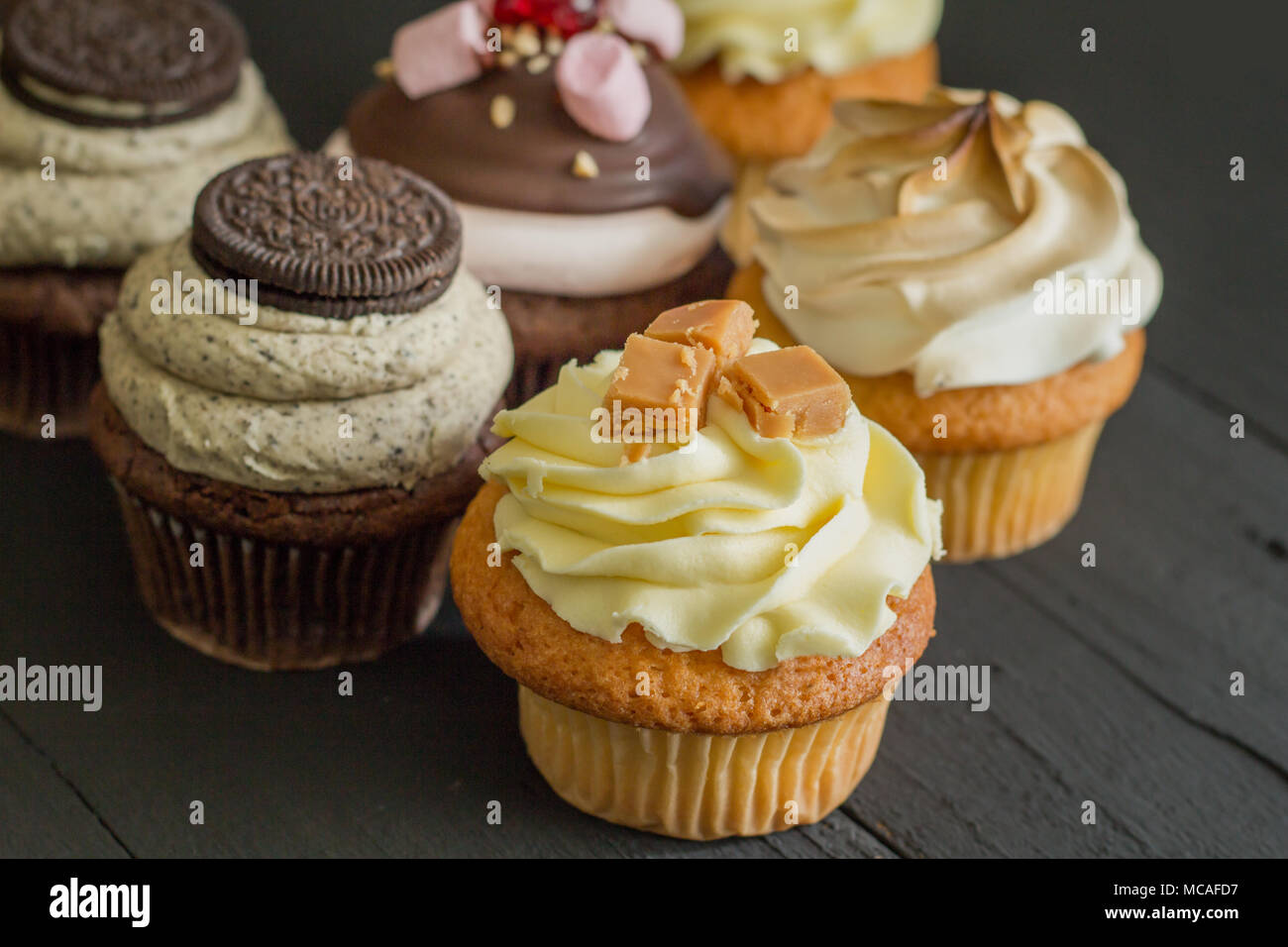 Decorated cup cakes on black table - selective focus Stock Photo