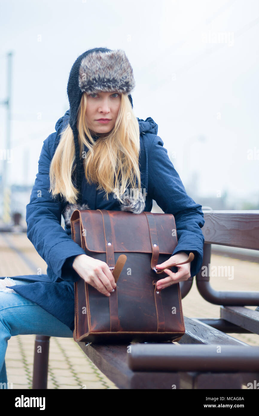 woman with leather handbag siting on bench Stock Photo