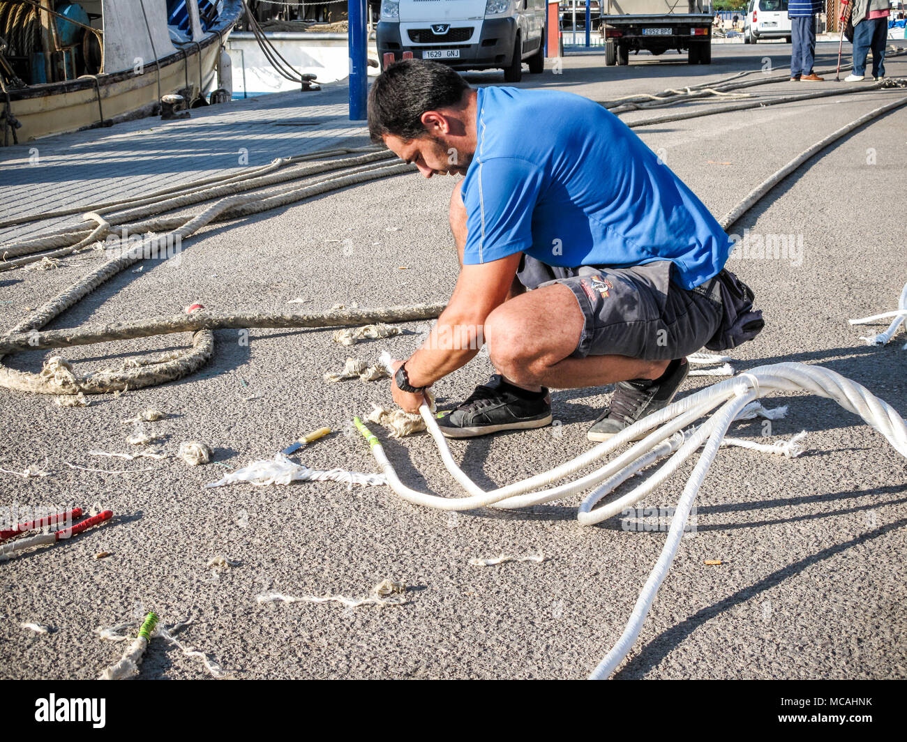 Fishermen mending ropes on a harbourside Stock Photo - Alamy