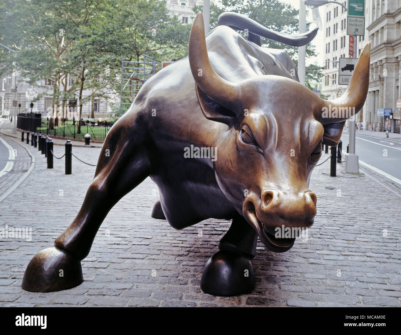 Charging Bull, which is sometimes referred to as the Wall Street Bull or the Bowling Green Bull, is a 3,200-kilogram (7,100?lb) bronze sculpture by Arturo Di Modica that stands in Bowling Green Park near Wall Street in Manhattan, New York City. Standing 11 feet (3.4?m) tall and measuring 16 feet (4.9?m) long. the oversize sculpture depicts a bull, the symbol of aggressive financial optimism and prosperity, leaning back on its haunches and with its head lowered as if ready to charge. The sculpture is both a popular tourist destination which draws thousands of people a day, as well as one of the Stock Photo