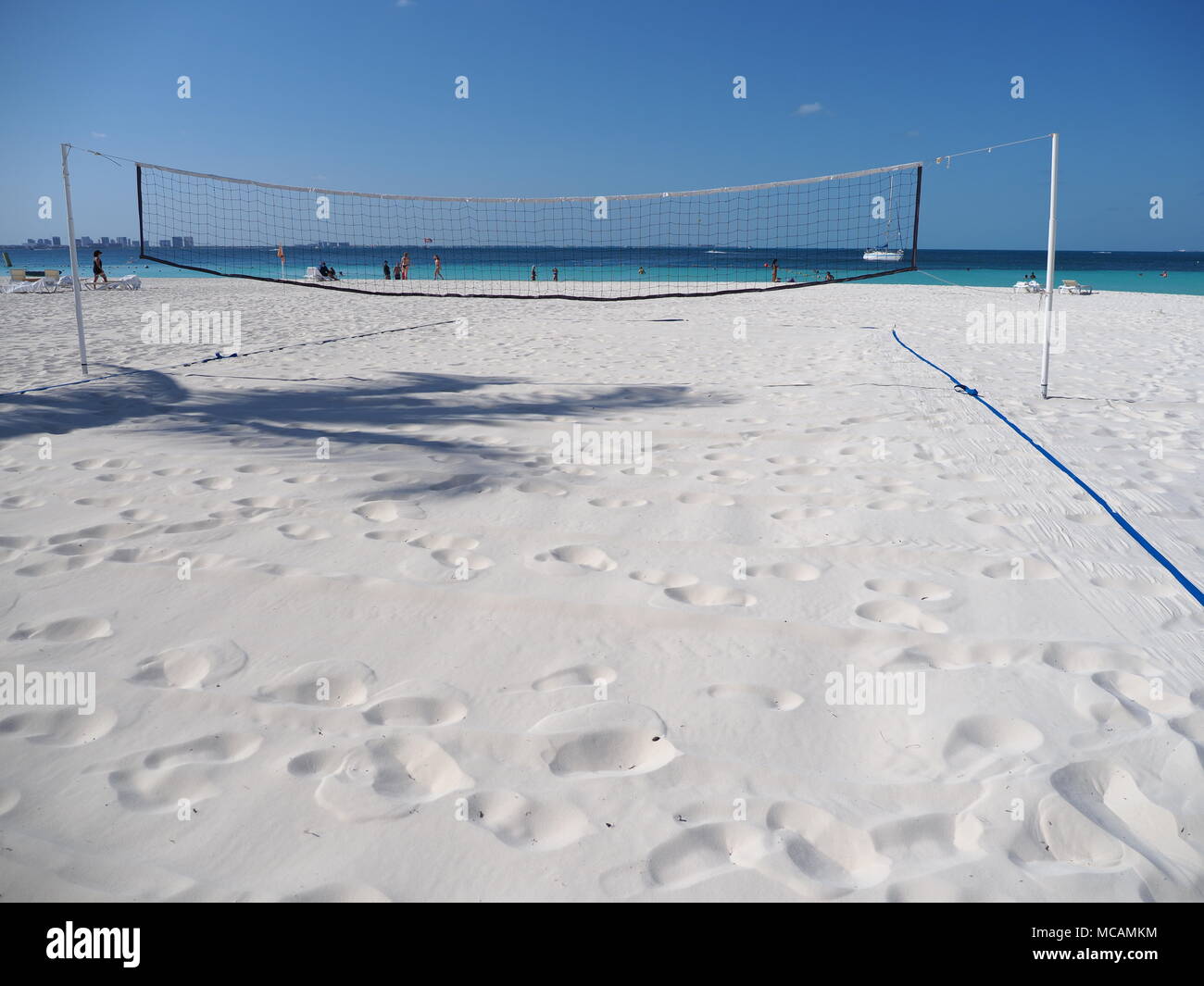Volleyball net and court on tropical sandy beach in Cancun city at Mexico with seaside of Caribbean Sea, shadow of exotic palm and clear blue sky in 2 Stock Photo