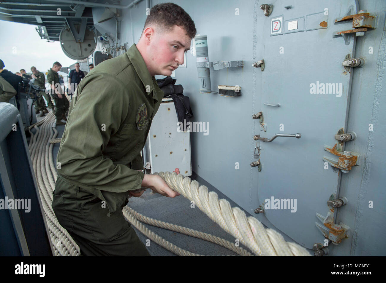 180202-N-DC385-231 WHITE BEACH, Okinawa (Feb. 2, 2018) Lance Cpl. Mark Weisenauer, from Bucyrus, Ohio, heaves a line during sea and anchor detail aboard the amphibious assault ship USS Bonhomme Richard (LHD 6) as the ship departs White Beach Naval Facility, Okinawa. Bonhomme Richard is operating in the Indo-Asia-Pacific region as part of a regularly scheduled patrol and provides a rapid-response capability in the event of a regional contingency or natural disaster. (U.S. Navy photo by Mass Communication Specialist 3rd Class Cosmo Walrath/Released) Stock Photo