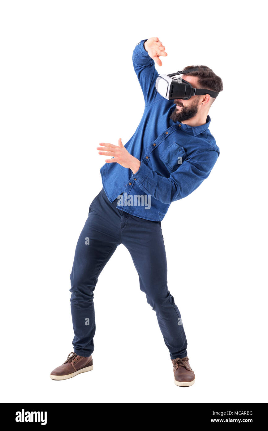 Young adult bearded man with vr glasses bending and shielding with hands playing video game. Full body isolated on white background. Stock Photo
