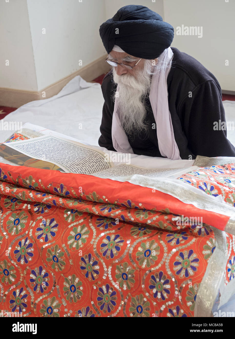 Sikh priest, a Granthi, reading Sri Guru Granth Sahib, which is the Holy Book in Sikhism. In Richmond Hill Queens, New York. Stock Photo