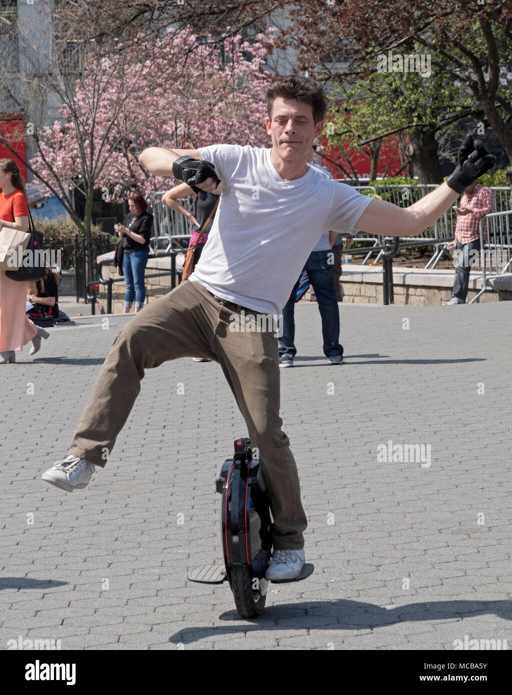 An Englishman living in New York riding an electric unicycle in Union Square Park in Manhattan, New York City. Stock Photo