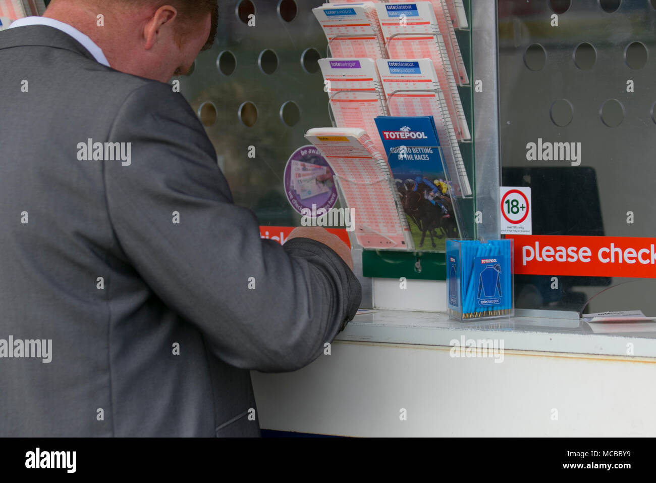 Man completing betting slip at TotePool, Aintree Racecourse, bookmaker, crowd, gambling, horse racing, horses, loose, money, people, racecourse, race horse, track, jockey, gamble, racetrack, tourism in Liverpool, UK Stock Photo