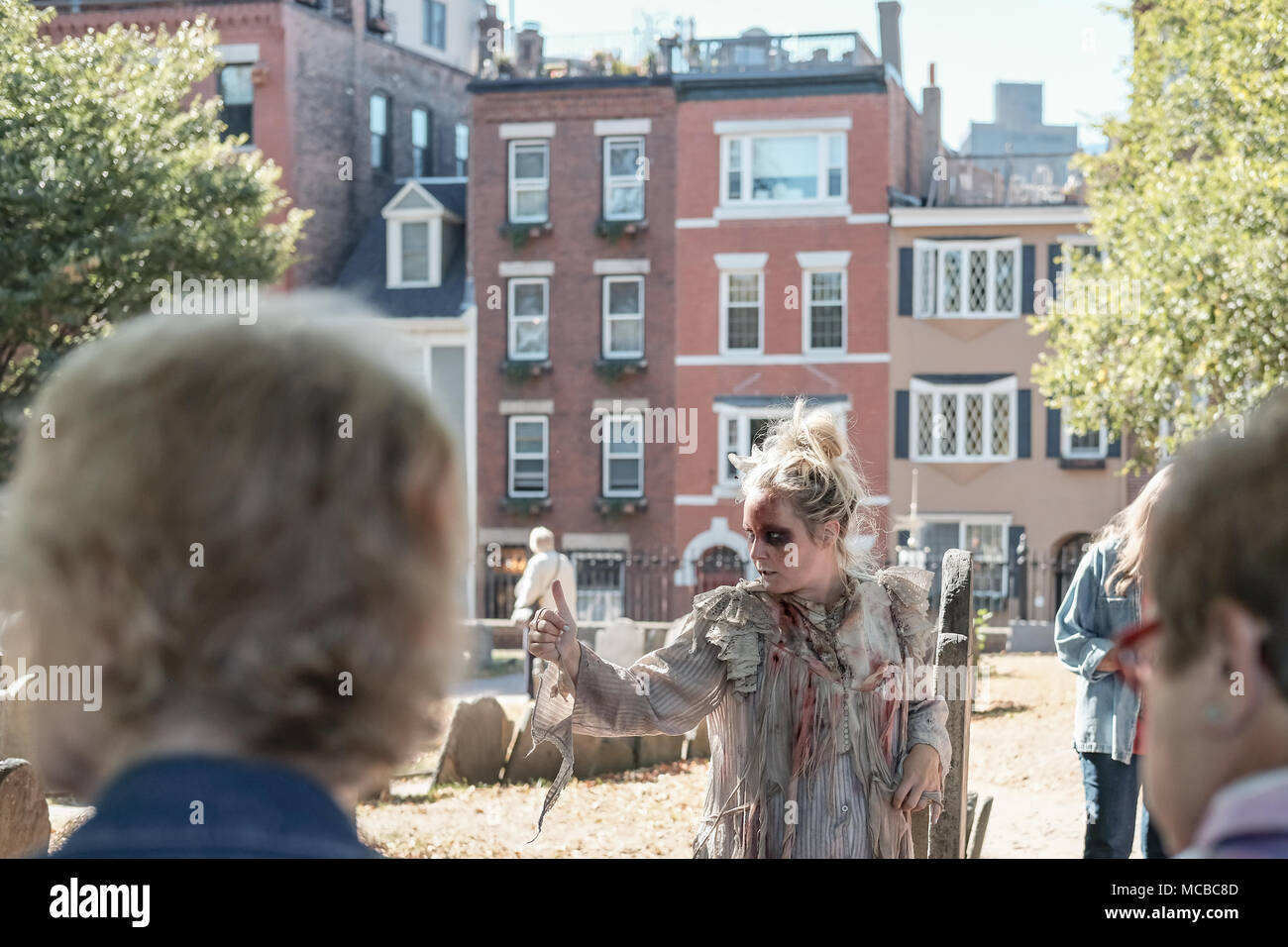 Shallow focus of a young entertainer dressed as a ghost seen conducting a history tour in a famous Boston graveyard during late summer. Stock Photo