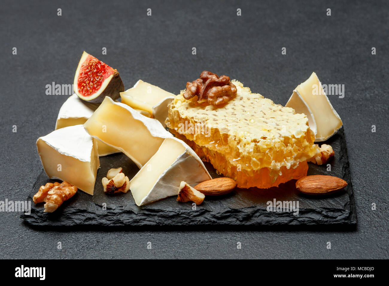 Camembert cheese with honey, figs, walnuts on stone board Stock Photo