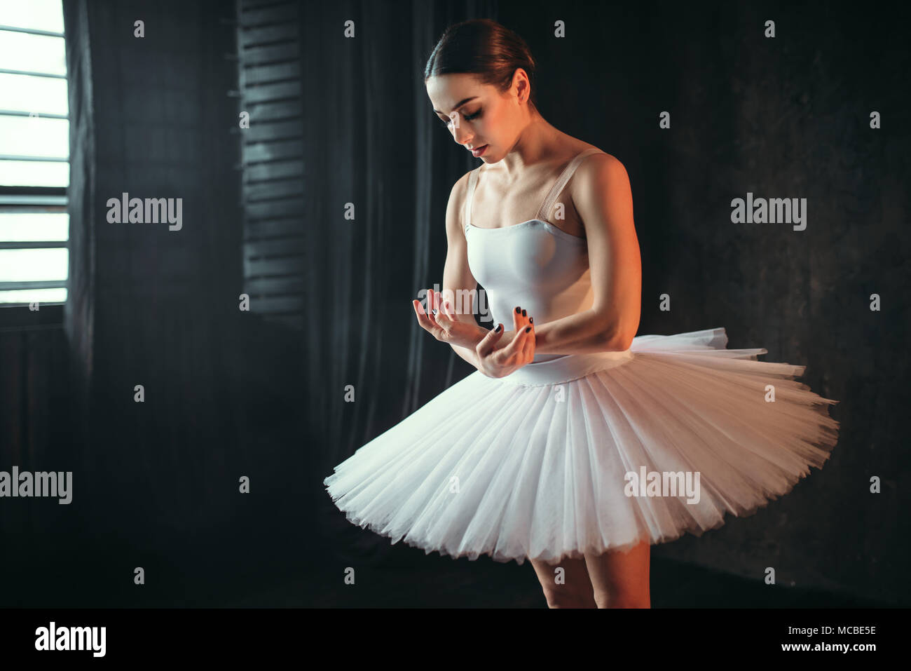 Ballerina dancing in studio against window Stock Photo