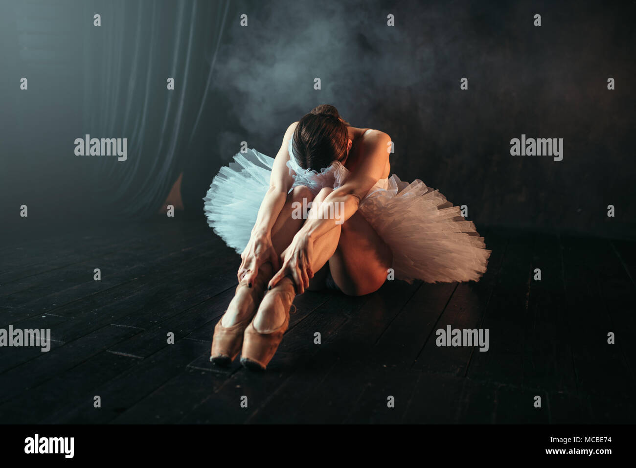 Ballet performer sits on floor, body flexibility Stock Photo