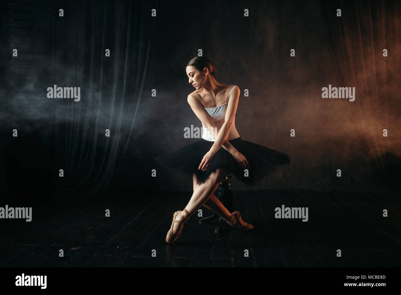 Ballet dancer sitting on black banquette Stock Photo