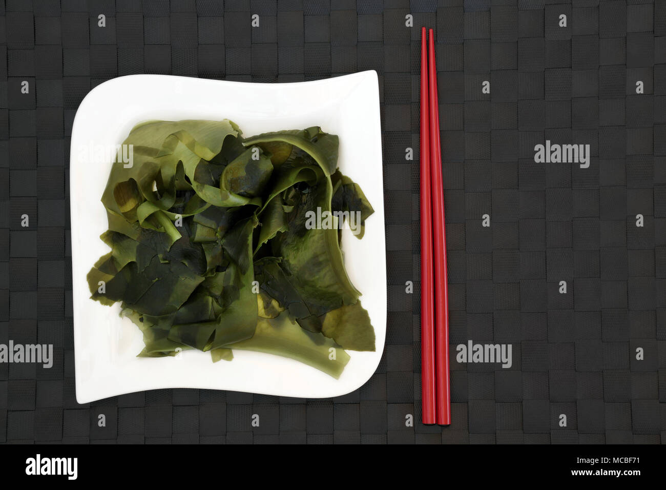 Japanese wakame seaweed food with on bamboo background with red chopsticks. Has many health benefits and is very high in minerals. Stock Photo