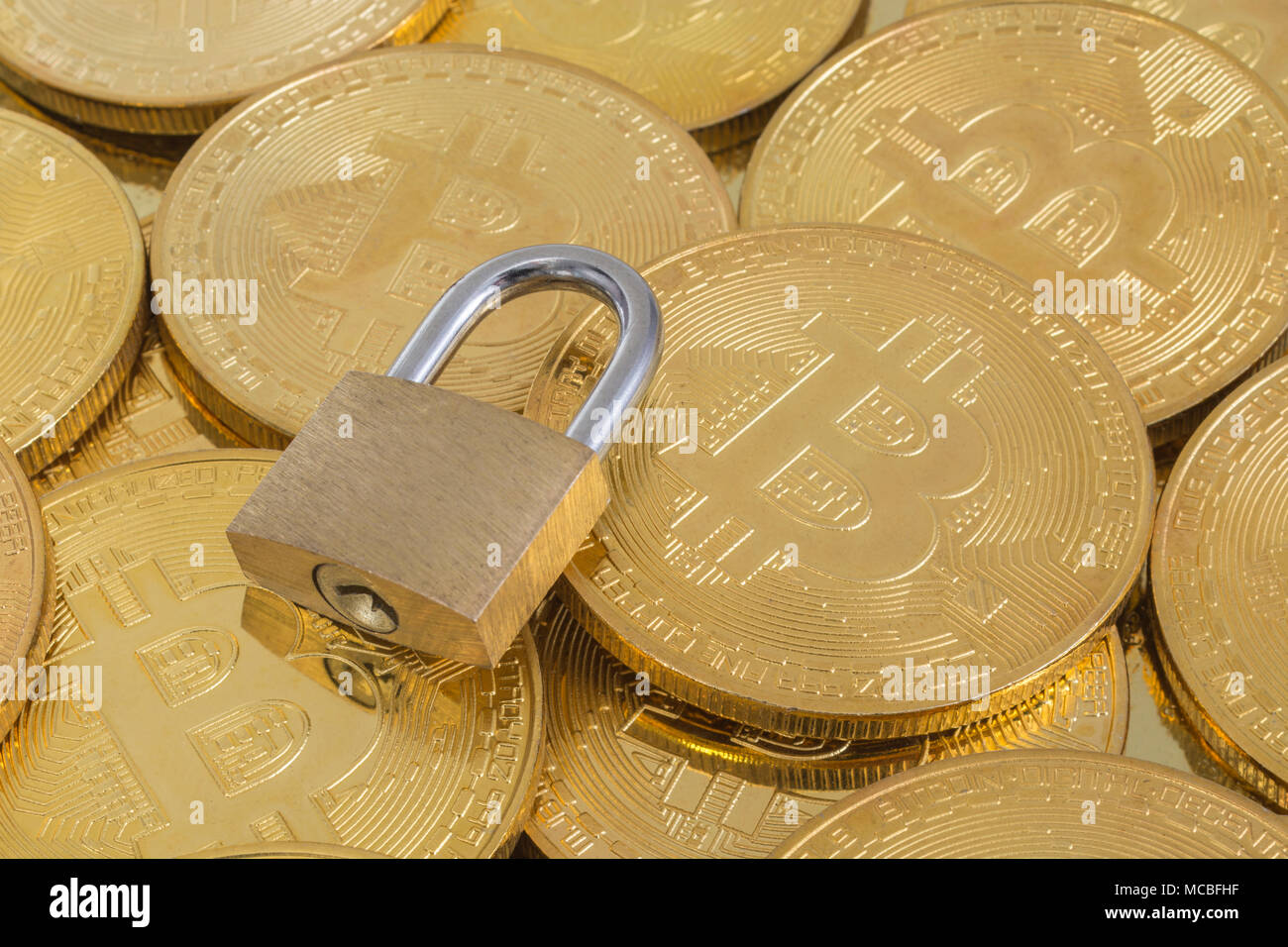 Macro-photo of small padlock with gold Bitcoins - as visual metaphor for Blochain / Bitcoin blockchain. China Bitcoin conference metaphor. Stock Photo