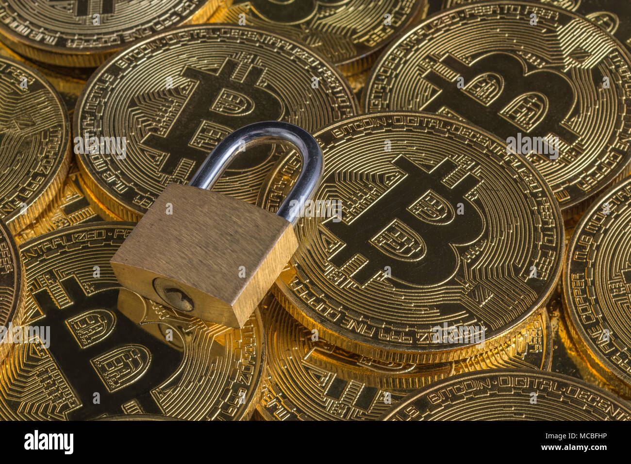 Macro-photo of small padlock with gold Bitcoins - as visual metaphor for Blochain / Bitcoin blockchain. China Bitcoin conference metaphor. Stock Photo