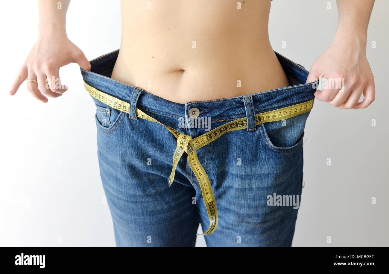 Thin woman in jeans measures waist, weight loss Stock Photo by