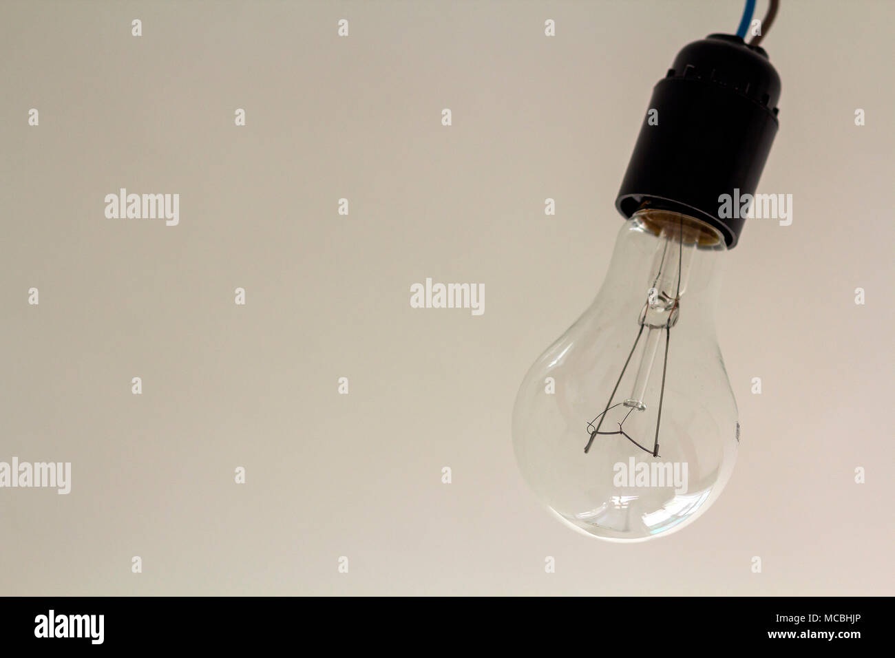 Close up picture of isolated electric light bulb on gray abstract background. Energy saving and economy concept. Stock Photo