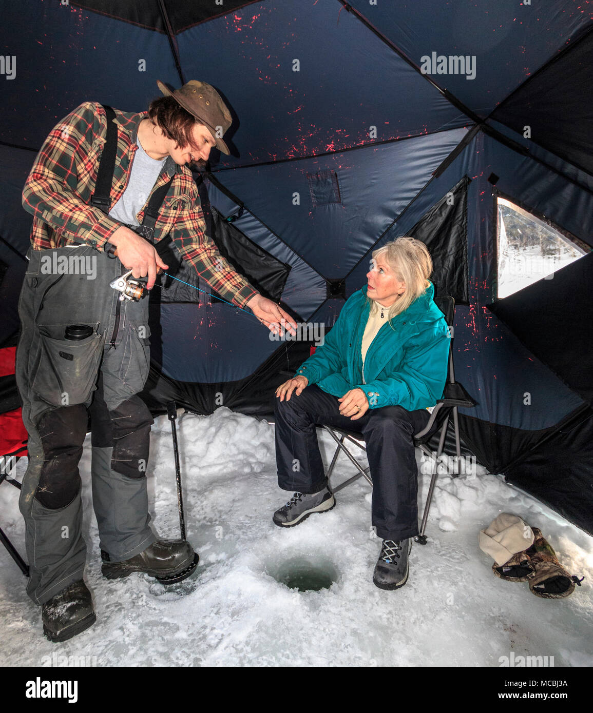 Ice fishing on Heffley Lake near Sun Peaks Resort with Elevated Fishing  Adventures. The lake is stocked with rainbow trout, a mild fish that makes  great eating. Guide Campbell Bryk shows a