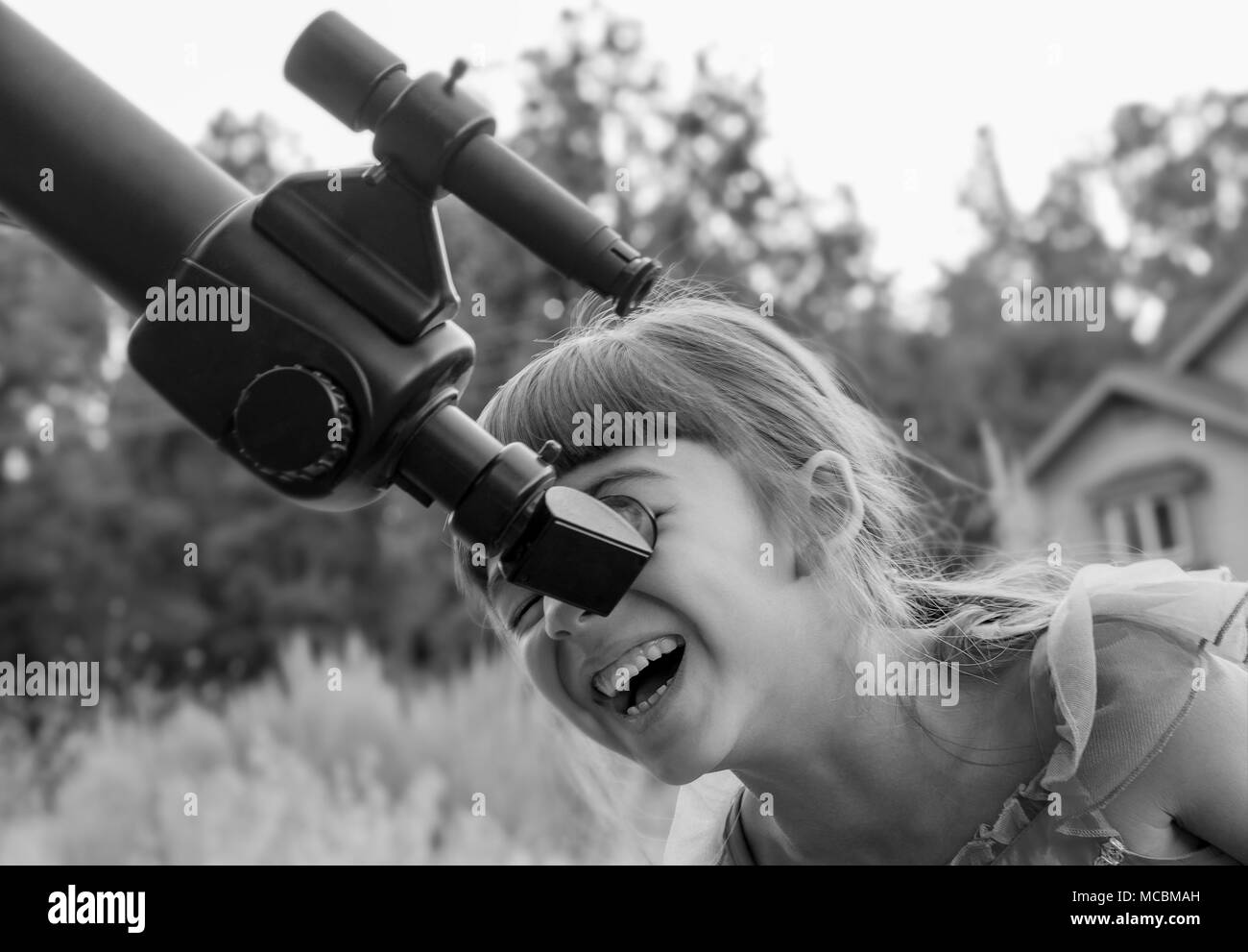 Cute Little Girl Looking Through a Telescope Stock Photo