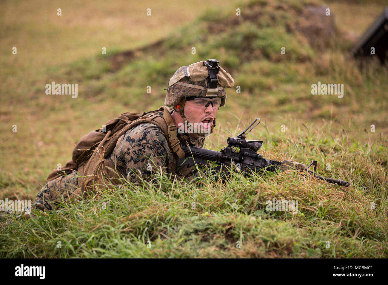 U.S. Marine Corps Lance Cpl. Beau Berg, a squad leader with Bravo Company (Bravo Co.), 1st Battalion, 3rd Marine Regiment, issues orders during a squad supported exercise at the Kaneohe Bay Range Training Facility, Marine Corps Base Hawaii, Mar. 22, 2018. Bravo Co. utilized machine gun suppression and mortar fire on simulated enemy forces, while infantrymen assaulted forward towards them. This combined-forces exercise was the last day of the battalion’s training event, Exercise Bougainville One, an annual training exercise that strengthens pre-deployment readiness. Stock Photo