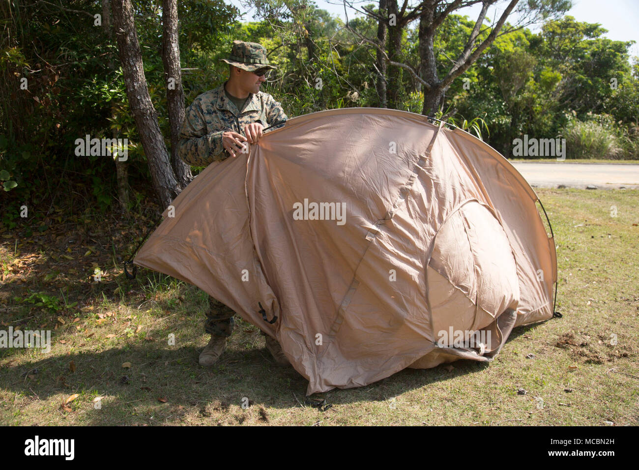 Lance Cpl. Kyle Harris, a combat engineer with 1st Platoon, A Co., 9th Engineer Support Battalion, 3rd Marine Logistics Group, sets up a tent to sleep in for the week while conducting vertical construction training, March 26, 2018, Camp Hansen, Okinawa, Japan.  The Marines stayed out in the field until the vertical construction of an ammunition storage point was completed, going to sleep around midnight every night and getting up around 6:00 a.m. every morning. Harris is a native of Antonio, Texas. Stock Photo