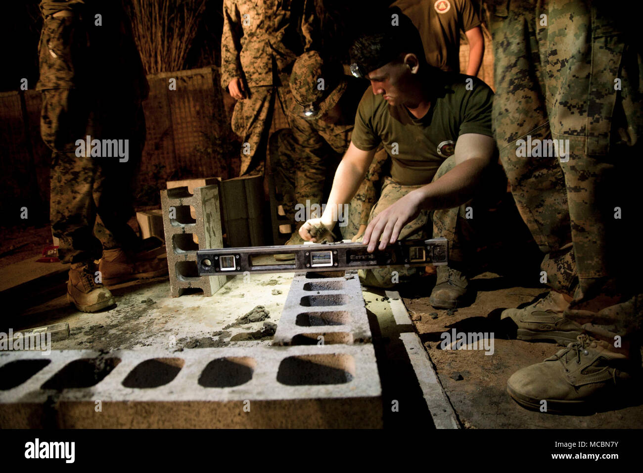Lance Cpl. Joseph Dickens, a combat engineer with 1st Platoon, A Co. 9th Engineer Support Battalion, 3rd Marine Logistics Group, lays bricks in the late evening March 26, 2018, Camp Hansen, Okinawa, Japan. The Marines stayed out in the field until the construction of an ammunition storage point was completed, using their safety vehicle and head lights to see late into the night. Vertical construction training prepares Marines for similar projects they will be entrusted with during humanitarian assistance operations. Dickens is a native of Beckley, West Virginia. Stock Photo
