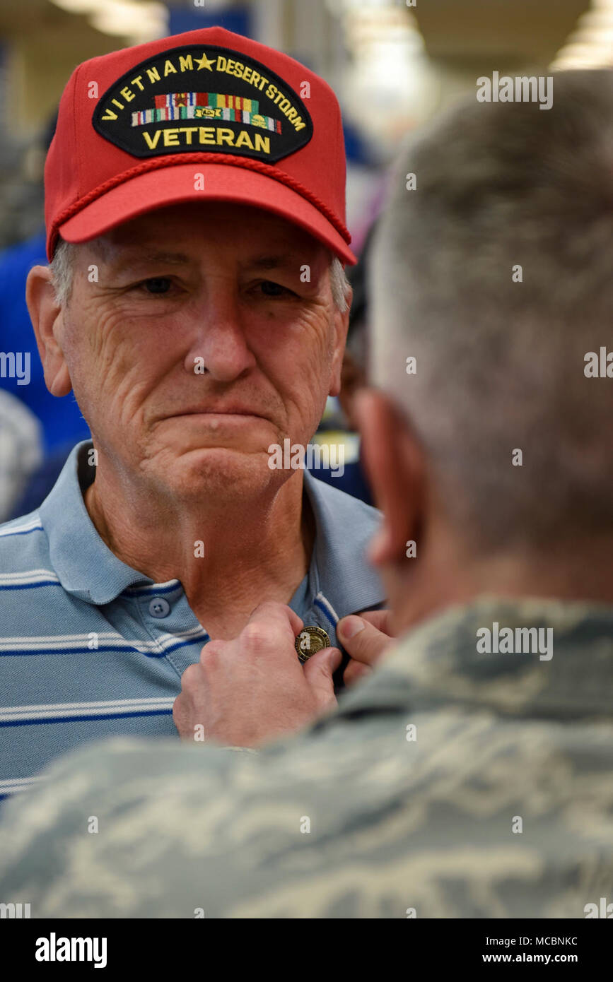 A Vietnam War veteran receives a commemorative pin from Col. Jason Knight, 4th Mission Support Group commander, during the National Vietnam War Veterans Day commemoration at The Exchange, March 29, 2018, at Seymour Johnson Air Force Base, North Carolina. Approximately 2.7 million Americans served in Vietnam during the conflict, with more than 58,000 losing their lives in defense of their country. Stock Photo