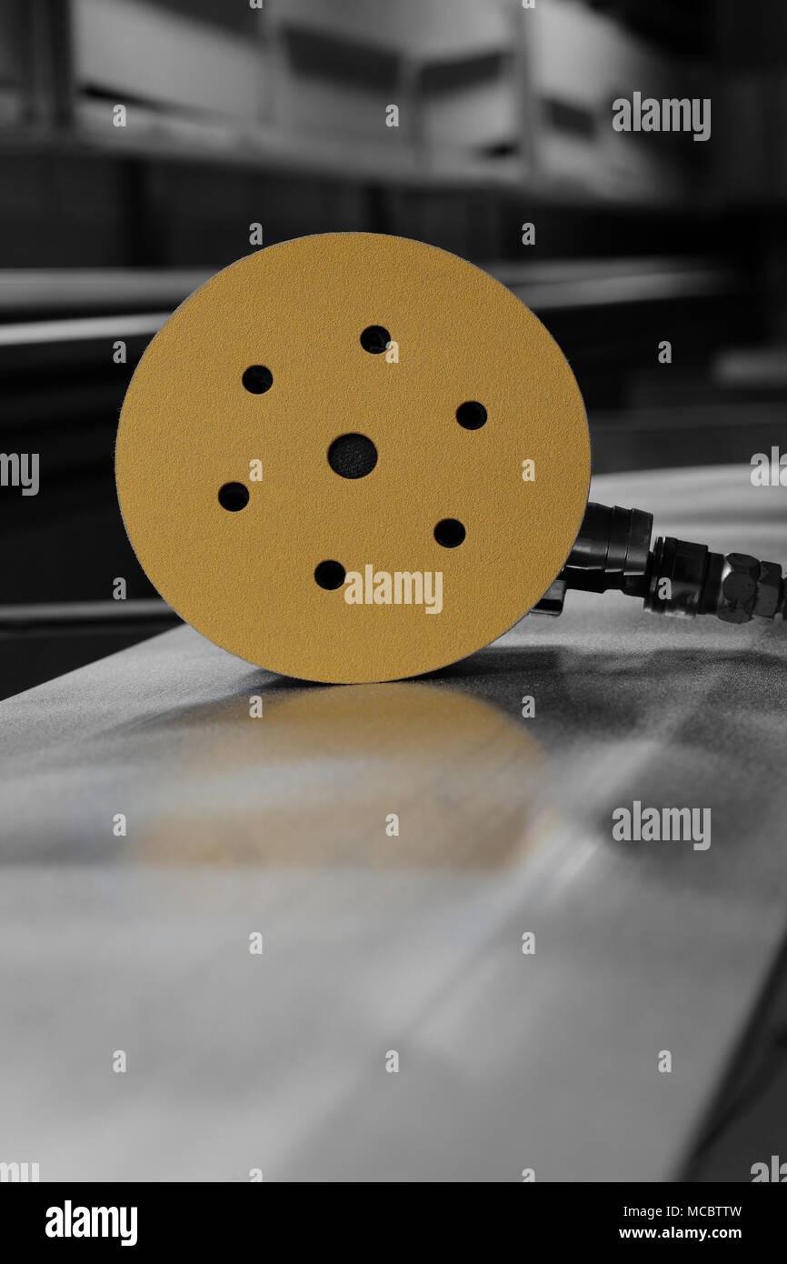 Orbital air sander with a sanding disc attached on a metal panel with