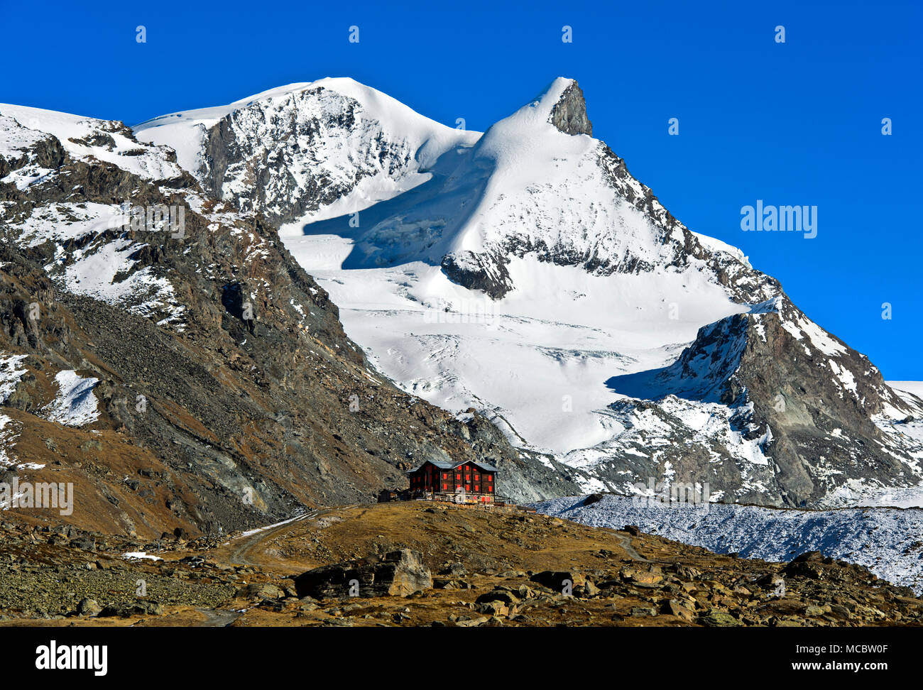 The historical Fluhalp mountain restaurant beneath the peaks Strahlhorn and Adlerhorn, Zermatt, Valais, Switzerland Stock Photo