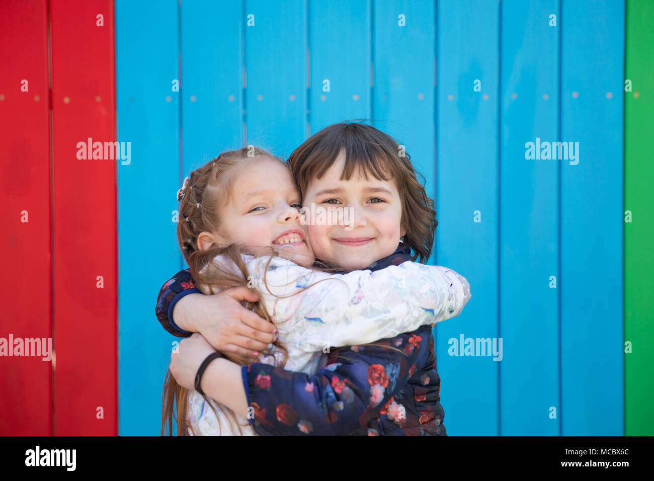 Outdoor portrait of two embracing cute little girls against a ...
