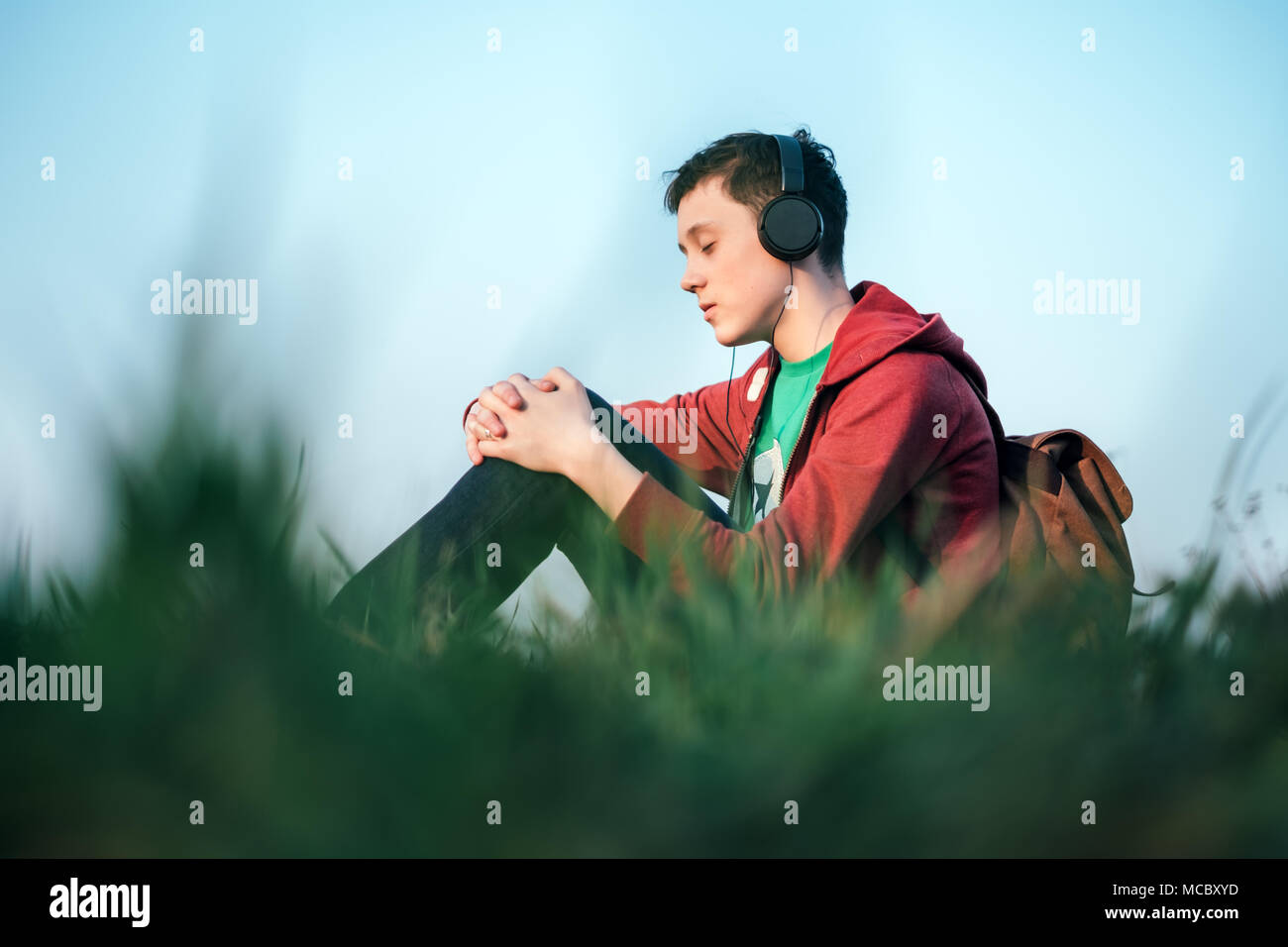 Teenager on green lawn listening music Stock Photo