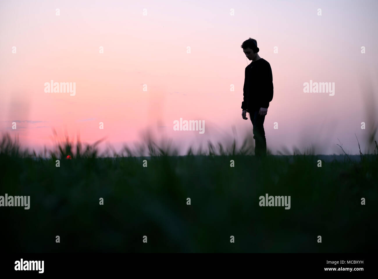 Teenager on green lawn listening music Stock Photo