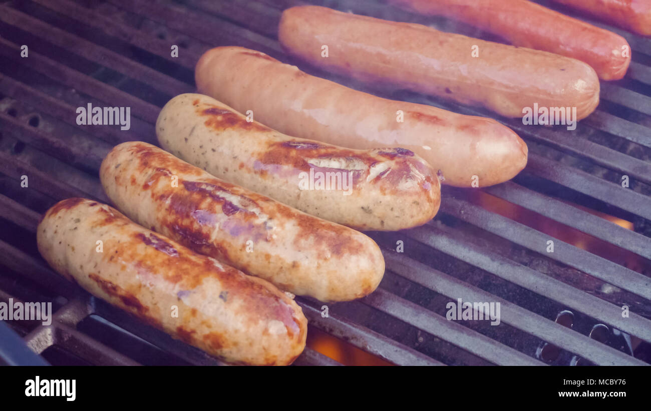 Cooking hot dogs and bratwurst on outdoor gas grill in the Summer Stock