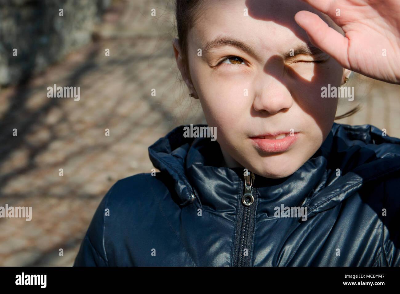 portrait of a girl looking at the sun and squinting eyes from the