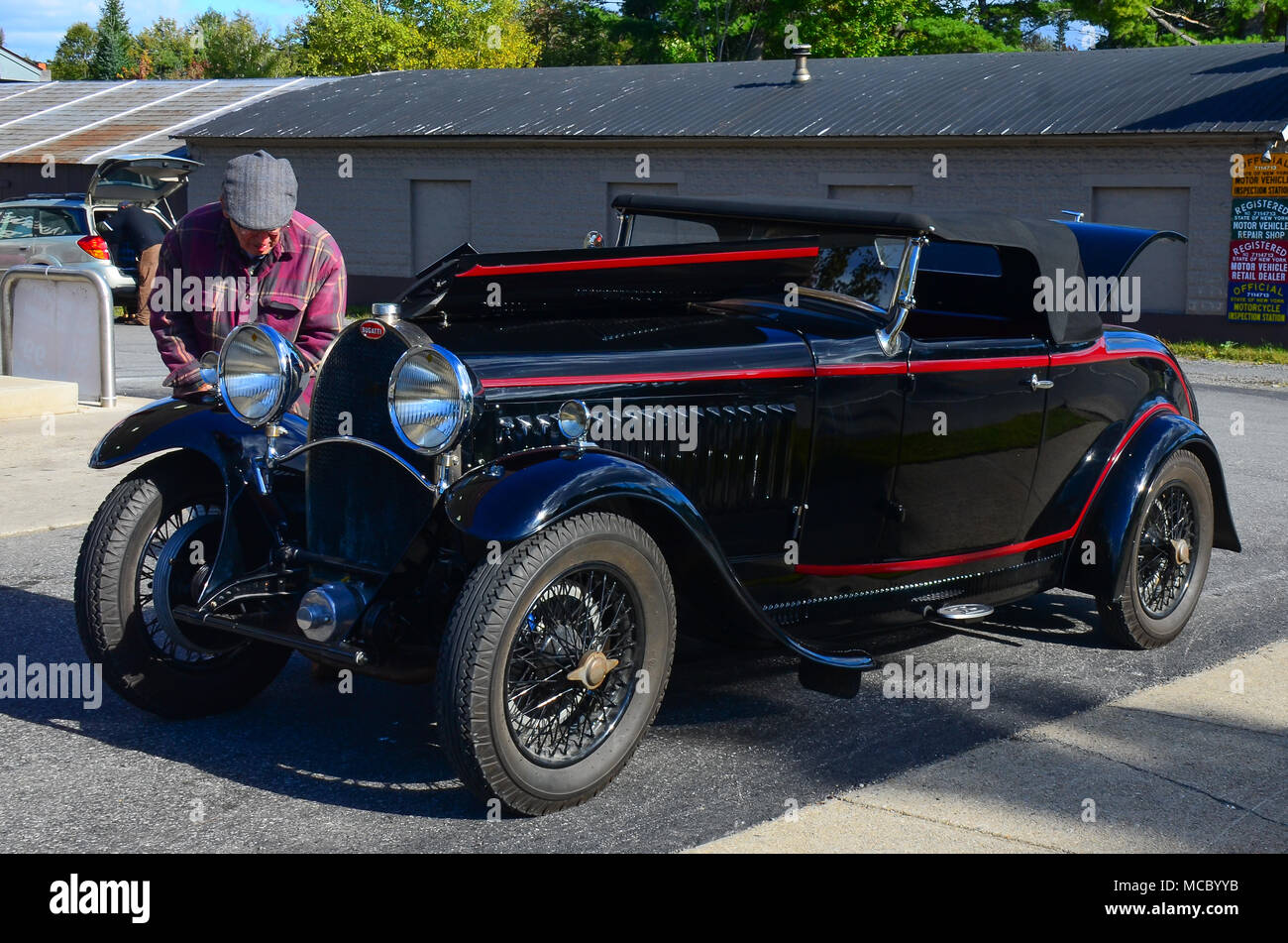 A black Bugatti roadster, Type 40, at a service station in Speculator, NY with the owner working on the engine as he tours the Adirondack Mountains. Stock Photo