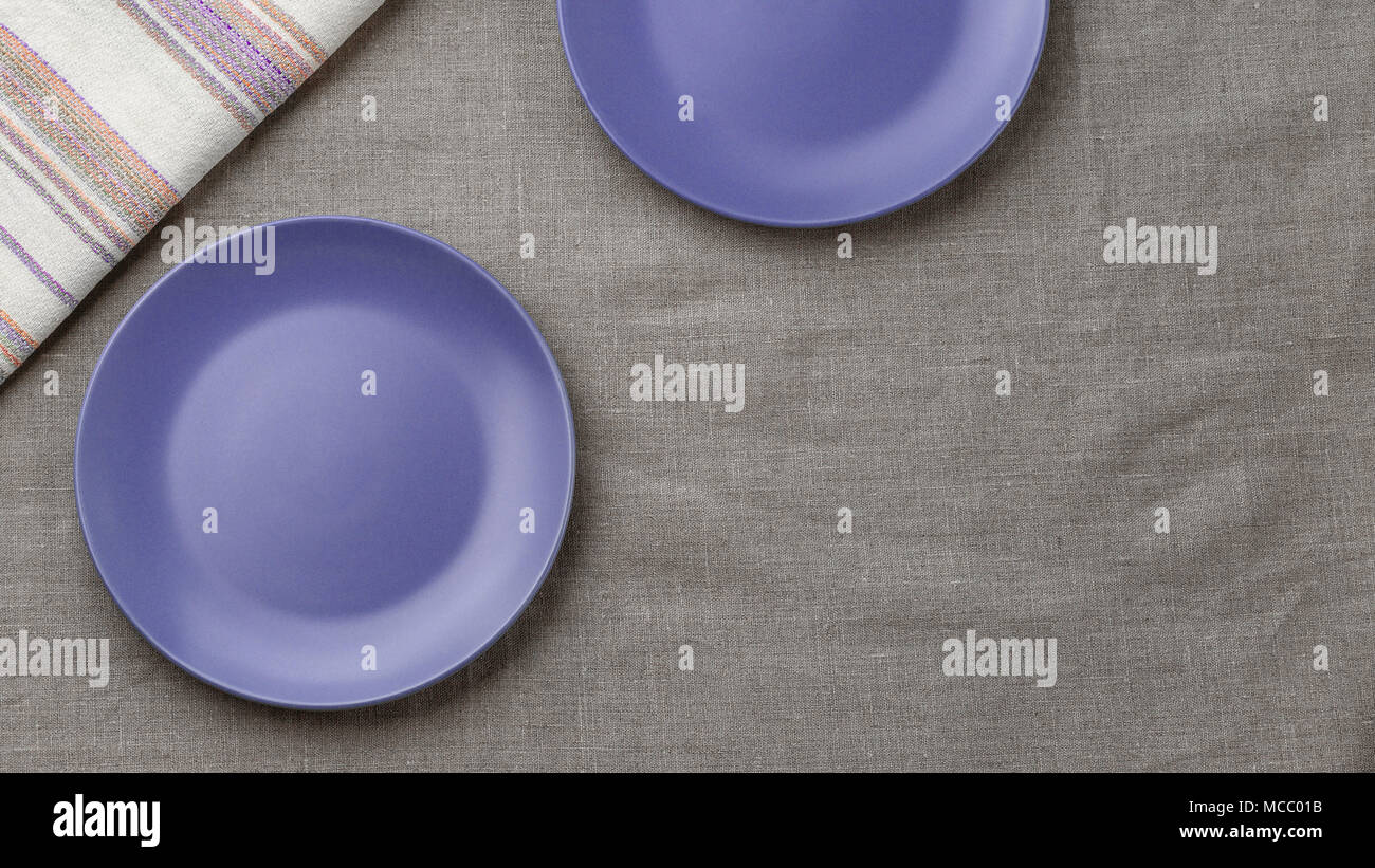Empty purple plates on grey burlap tablecloth background Stock Photo